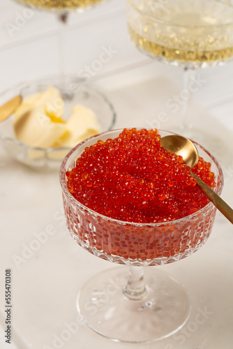 Red caviar in a glass vase on the table with glasses of champagne