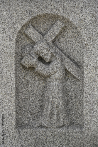 Carved stone figure carrying a cross seen on water fountain outside Church of St Nicolas; La Coruna, Spain photo