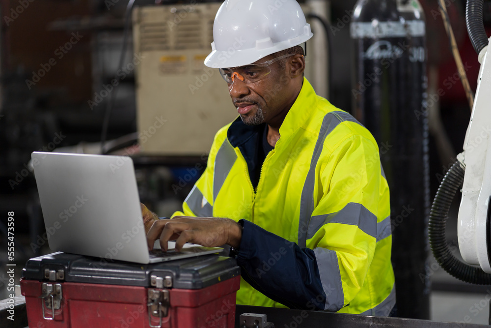 Male engineer worker using laptop computer working in the workshop in workshop. Male worker working with laptop computer in the factory. Industry manufacturing technology Male engineer worker using laptop computer working in the workshop in workshop. Male worker working with laptop computer in the factory. Industry manufacturing technology