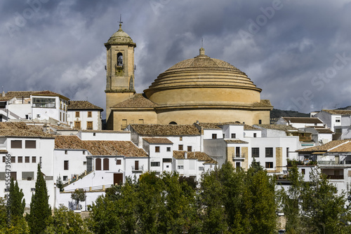 Bell tower and domed roof of Iglesia de la Encarnacion church with white houses below; Montefrio, Province of Granada, Spain photo