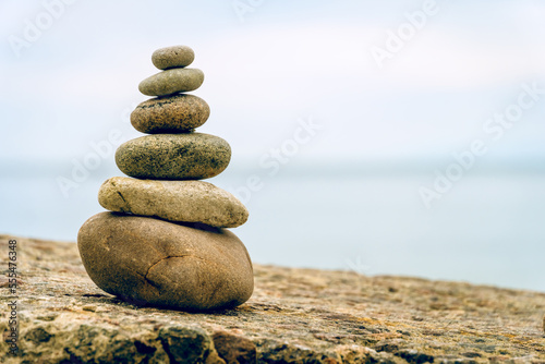 Stacked stones on beach on the rock. Shape of a pyramid. Concept zen, harmony, balance. Selective focus.