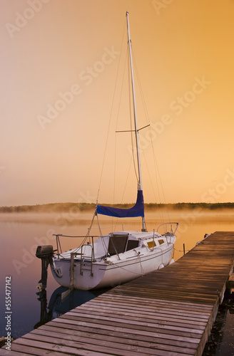 Sailboat at a dock on Hanging Heart Lakes at sunrise, Prince Albert National Park; Saskatchewan, Canada photo