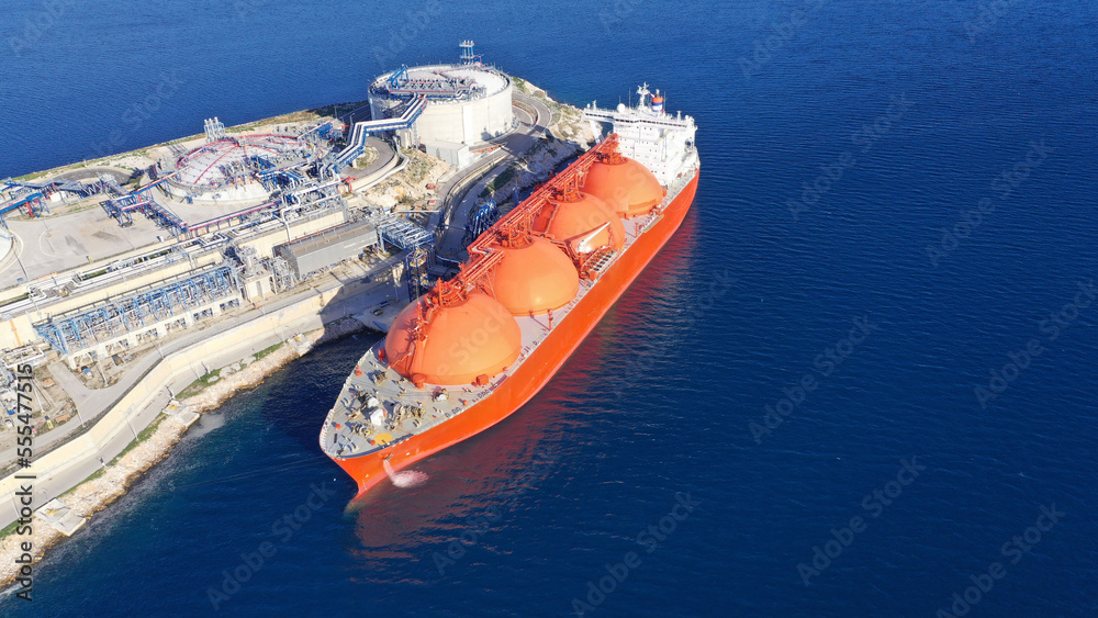 Aerial drone photo of LNG (Liquified Natural Gas) tanker anchored in small LNG industrial islet of Revithoussa equipped with tanks for storage, Salamina, Greece