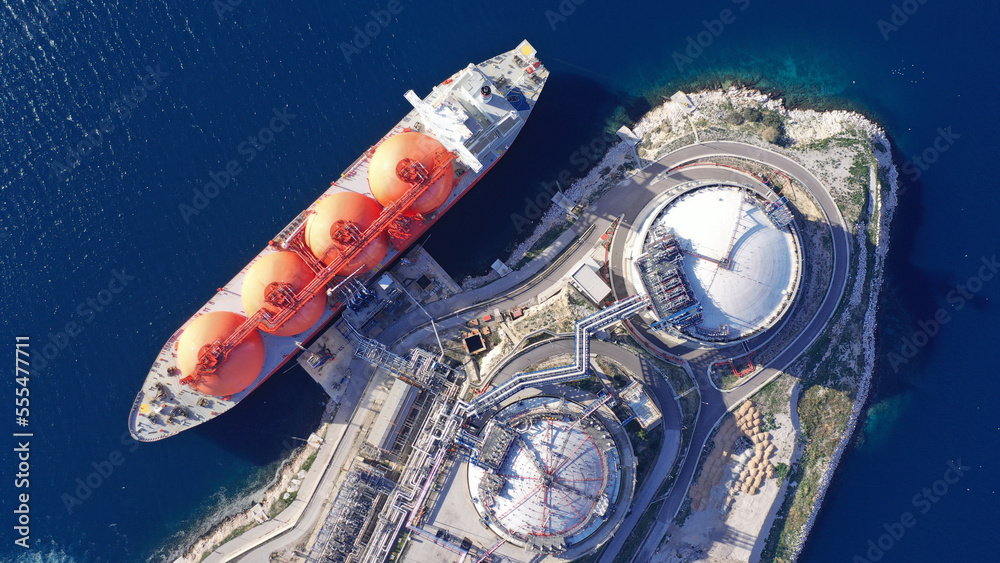 Aerial drone top down photo of LNG (Liquified Natural Gas) tanker anchored in small gas terminal island with tanks for storage to store and regasify LNG - obrazy, fototapety, plakaty 