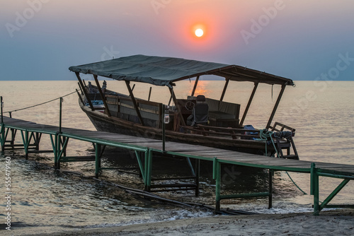 Sun setting behind boat moored to dock at Mbali Mbali Mahale Lodge (Kungue Beach Lodge) on Lake Tanganyika; Tanzania photo