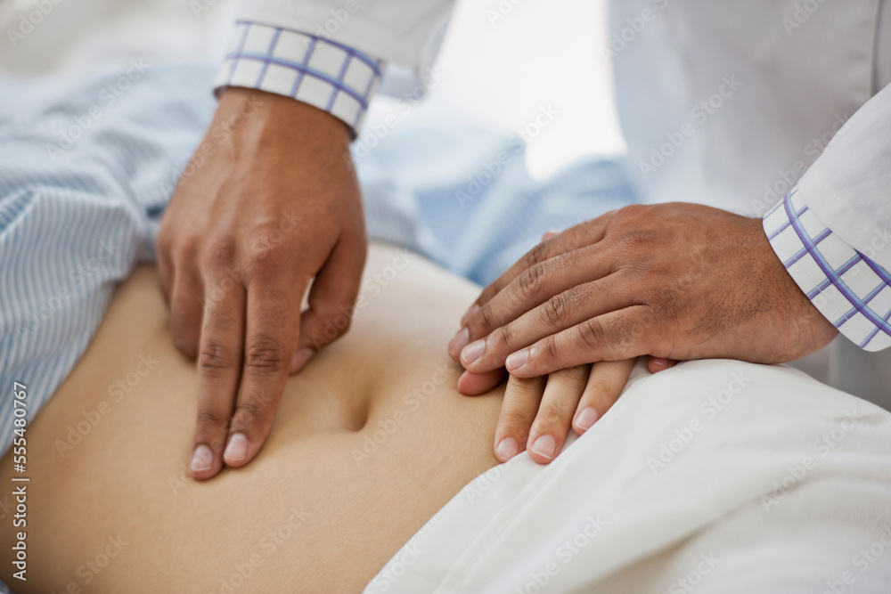Doctor's hands examining a female patient's abdomen Doctor's hands examining a female patient's abdomen