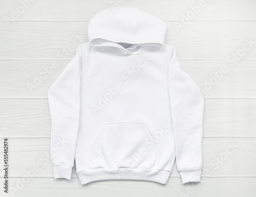 White fashionable kid sweatshirt with a hood with clothes hanger on white background top view. Fashionable unisex clothing, hoodie, casual youth style, sports. Blank hoody mock up