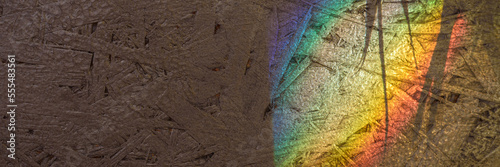 Bright rainbow light spot and shadows on textured plywood surface close view. Wonderful effect and physics laws demonstration, soft focus, abstract web banner