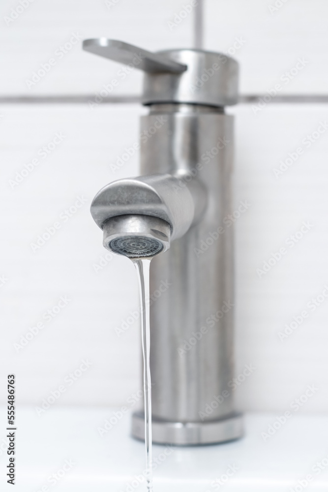 Water flows from the faucet in the bathroom. Water faucet close-up. Saving water. The faucet needs repair Water flows from the faucet in the bathroom. Water faucet close-up. Saving water. The faucet needs repair