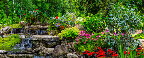 Landscaped flower garden in bloom with water feature in a yard; Hudson, Quebec, Canada