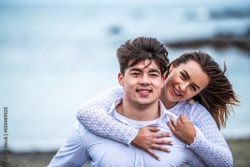 Portrait of a young couple with windblown hair on the beach; Wellington, North Island, New Zealand Portrait of a young couple with windblown hair on the beach; Wellington, North Island, New Zealand