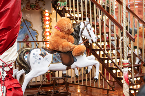 carousel in the form of a horse with a red teddy bear toy in the New Year's city in winter