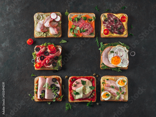Set of eight different sandwiches with meat in square shape, copy space for text in center. Top view or flat lay. Assortment meat toasts on black background. Idea, creative concept for sausage maker
