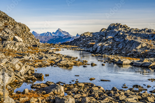 Rocky landscape with water and rugged mountain peaks in the distance; Sermersooq, Greenland photo