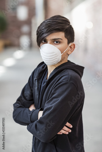 Pre-teen boy stands wearing a protective mask to protect against COVID-19 during the Coronavirus World Pandemic; Toronto, Ontario, Canada photo