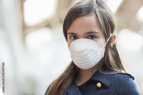 Young girl stands wearing a protective mask to protect against COVID-19 during the Coronavirus World Pandemic; Toronto, Ontario, Canada photo