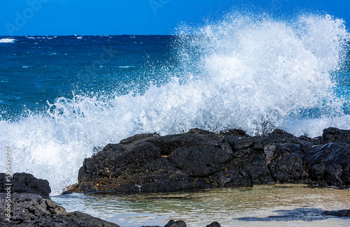 Waves crashing and splashing on lava rock along the shore of Kaupo Cove; Oahu, Hawaii, United States of America photo