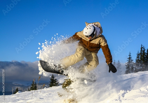 snowboarder doing freestyle trick on a sunny day under the blue sky in a powder snow