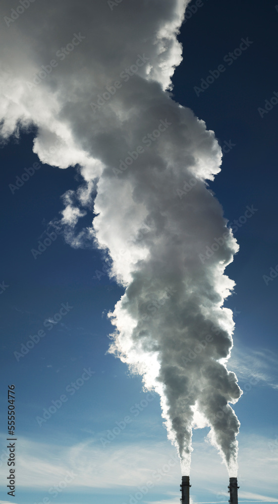 Close-up of industrial smoke stacks with steam billowing into blue sky, Toronto, Ontario, Canada Close-up of industrial smoke stacks with steam billowing into blue sky, Toronto, Ontario, Canada