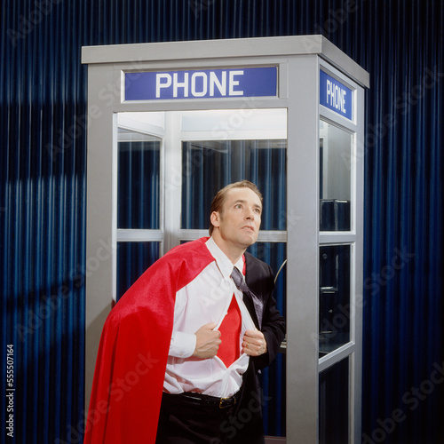 Man Opening Shirt to Reveal Super Hero Costume in Phone Booth photo