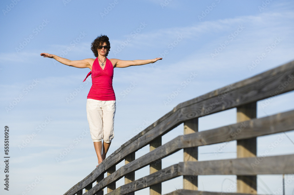 Woman Balancing on Wooden Railing, Honeymoon Island State Park, Florida, USA Woman Balancing on Wooden Railing, Honeymoon Island State Park, Florida, USA