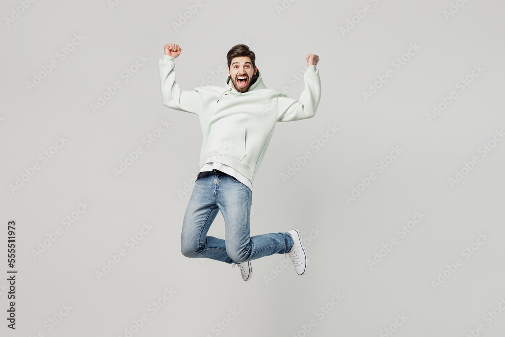 Full body young overjoyed excited satisfied fun caucasian man wear mint hoody look camera jump high do winner gesture isolated on plain solid white background studio portrait People lifestyle concept Full body young overjoyed excited satisfied fun caucasian man wear mint hoody look camera jump high do winner gesture isolated on plain solid white background studio portrait People lifestyle concept