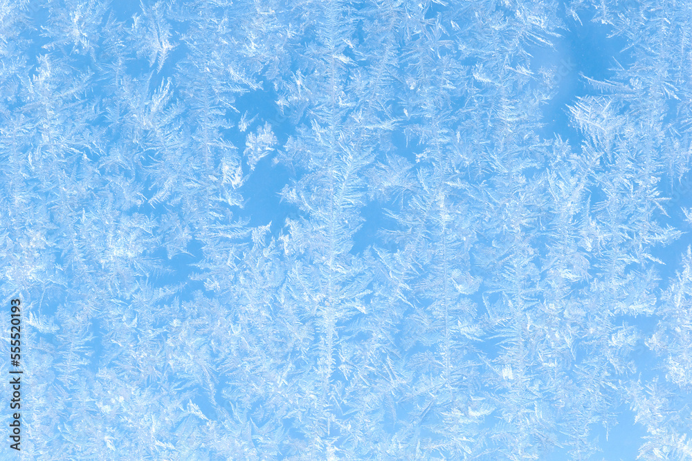 Blue background. Beautiful pattern of frost on the window against the blue sky. Blue background. Beautiful pattern of frost on the window against the blue sky.