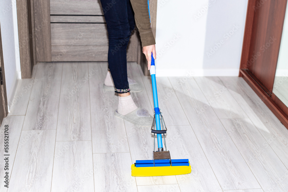 A woman washes the laminate floor in the apartment with a mop. House cleaning. A woman washes the laminate floor in the apartment with a mop. House cleaning.