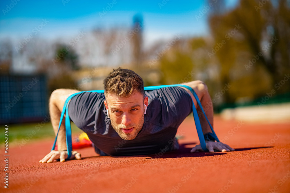 Man with athletic body performs exercises using a resistance band. Man with athletic body performs exercises using a resistance band.