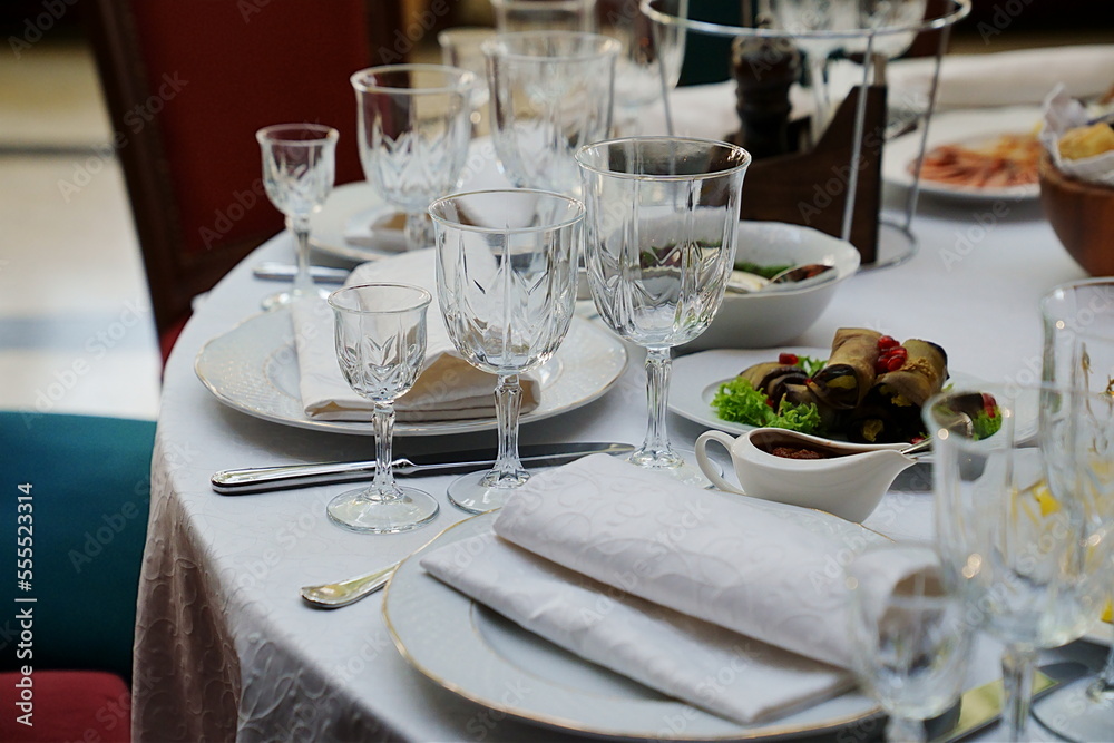 Fototapeta premium table setting for a festive dinner. empty wine glasses, tableware and snacks.