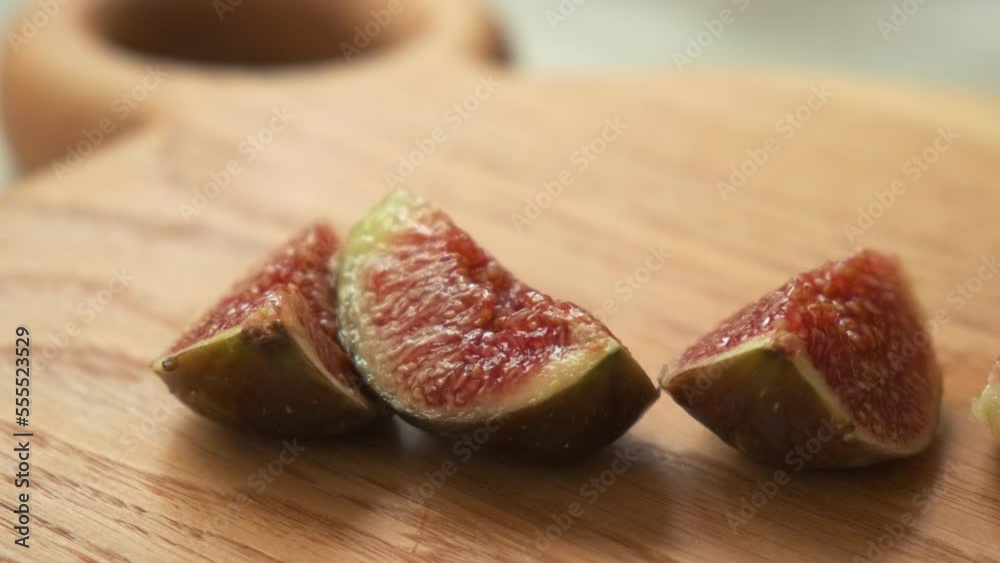 fresh cut figs close up. View of cutting fig fruit with knife. the girl cuts figs. women's hand cut ripe figs with a knife on a wooden board. women's hands spread sliced figs on a plate fresh cut figs close up. View of cutting fig fruit with knife. the girl cuts figs. women's hand cut ripe figs with a knife on a wooden board. women's hands spread sliced figs on a plate