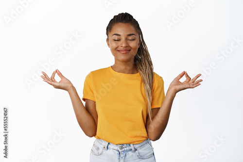 Zen, nirvana and mindfulness. Smiling peaceful Black girl close eyes and smile, practice yoga, meditating and breathing relaxed, white background