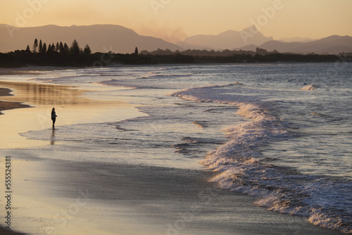 Silhouette of person on beach watching the waves hitting the shore at Byron Bay in New south Wales, Australia photo