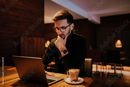 Young businessman using laptop for online meeting while sitting in modern cafe