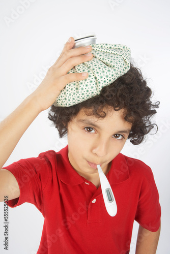 Boy With a Thermometer in His Mouth and an Ice Pack on His Head photo