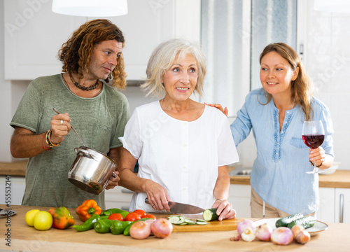 Positive aged woman spending time with her family  cooking tasty meals for dinner