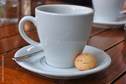  a cup of coffee served with a cookie on wooden table. Vintage, romantic coffee concept