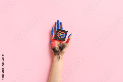 Photos Painted female hand and paper with symbols of polyamory on pink background