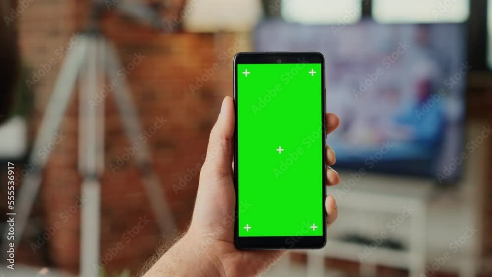 Office worker working with greenscreen template on mobile phone, using smartphone with blank background and chroma key display. Looking at isolated mock up copy space. Close up.
