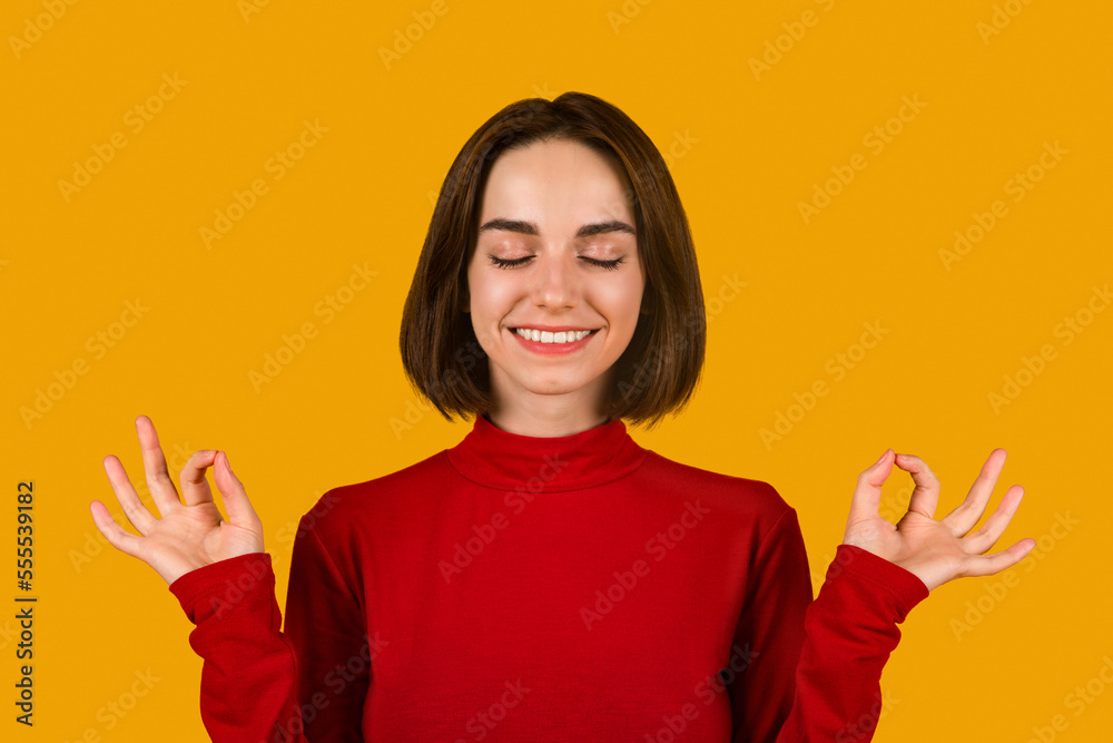 Calm concentrated woman meditating with closed eyes and zen fingers Calm concentrated woman meditating with closed eyes and zen fingers