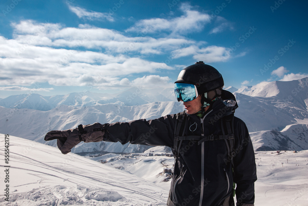 A traveler in a ski mask points to the left towards the high mountains of the Caucasus