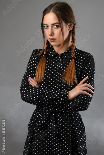 portrait of a mysterious girl with pigtails and a black dress.grey background with smoke
