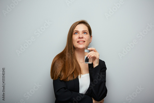 Smiling woman holding water glass looking up. isolated female portrait with black suit.