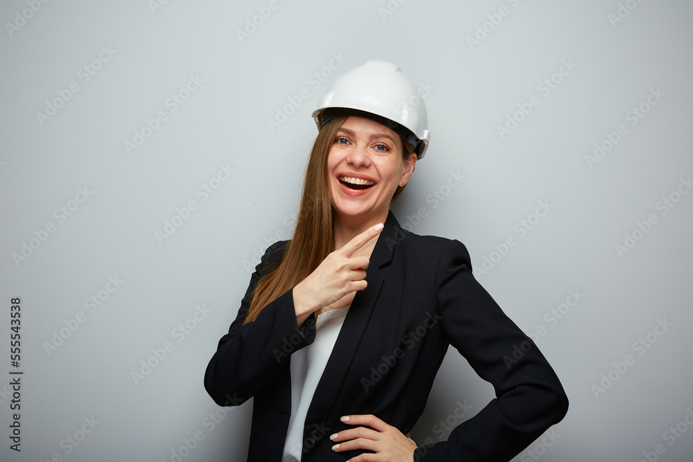 Smiling woman architect in safety helmet pointing finger at side. Isolated female portrait. Smiling woman architect in safety helmet pointing finger at side. Isolated female portrait.