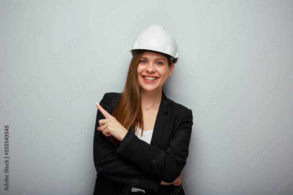 Smiling woman architect in safety helmet pointing finger at side. Isolated female portrait. Smiling woman architect in safety helmet pointing finger at side. Isolated female portrait.