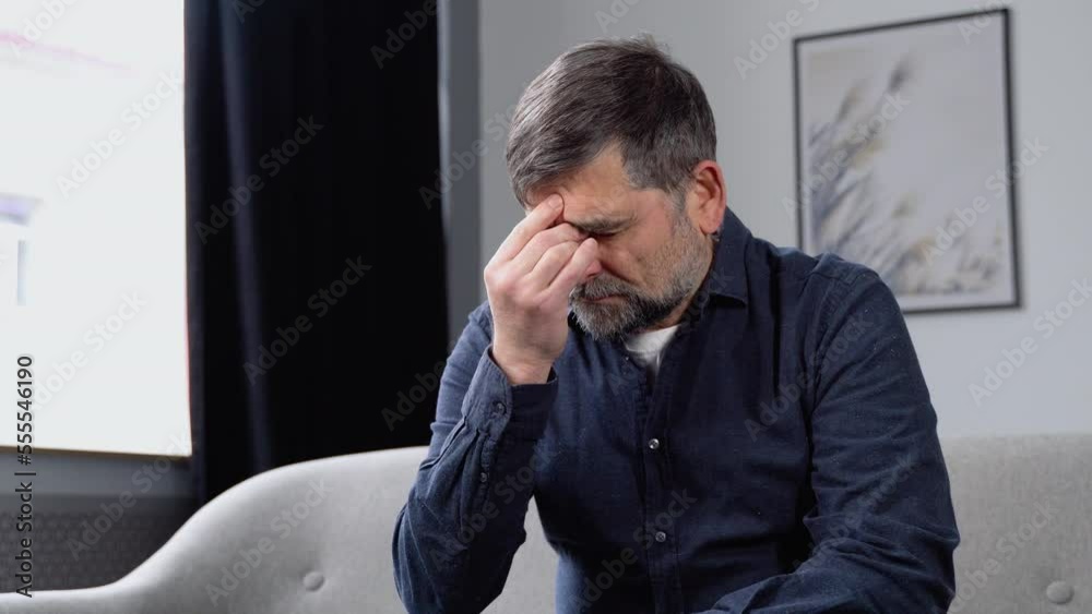 Sad senior man with headache sitting alone in a empty room Sad senior man with headache sitting alone in a empty room
