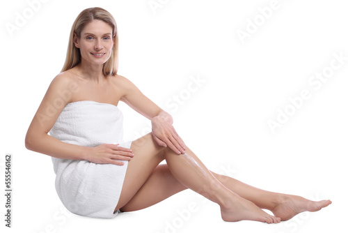 Woman applying body cream onto her leg against white background