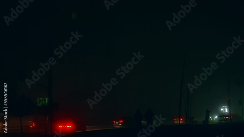 Two dark silhouettes of men walking along the road full of cars. Blackout time in Ukraine after russian drone and missiles attacks. City in darkness from energy outage. photo