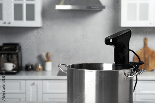 Pot with sous vide cooker in kitchen, closeup and space for text. Thermal immersion circulator