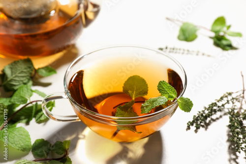 Aromatic herbal tea with mint and thyme on white table, closeup